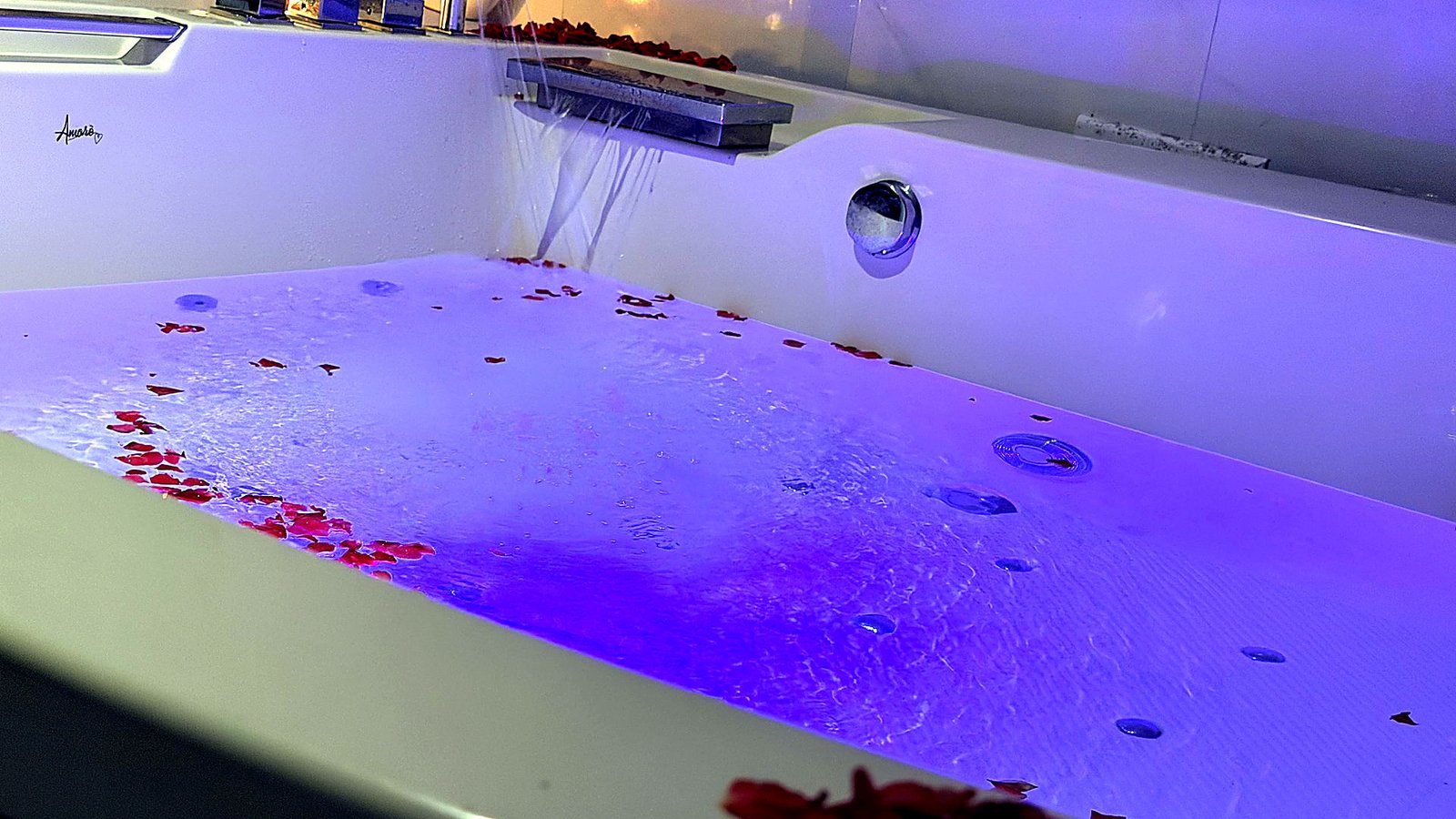 Jacuzzi bath with rose petals under blue mood lighting